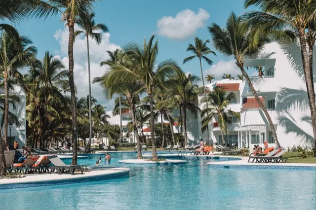 Piscina de un resort entre palmeras y edificios blancos