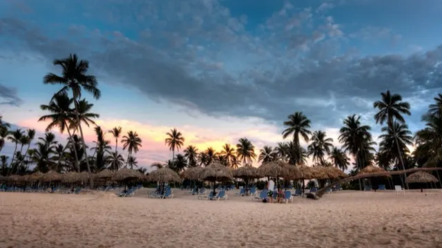 Atardecer entre palmeras y techos de palma en la playa