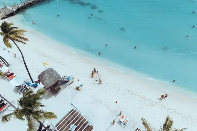 Vista aérea de una playa de arena blanca y agua turquesa con bañistas