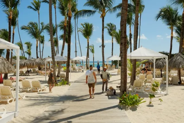 Zona de playa de un resort con cabañas blancas y palmeras